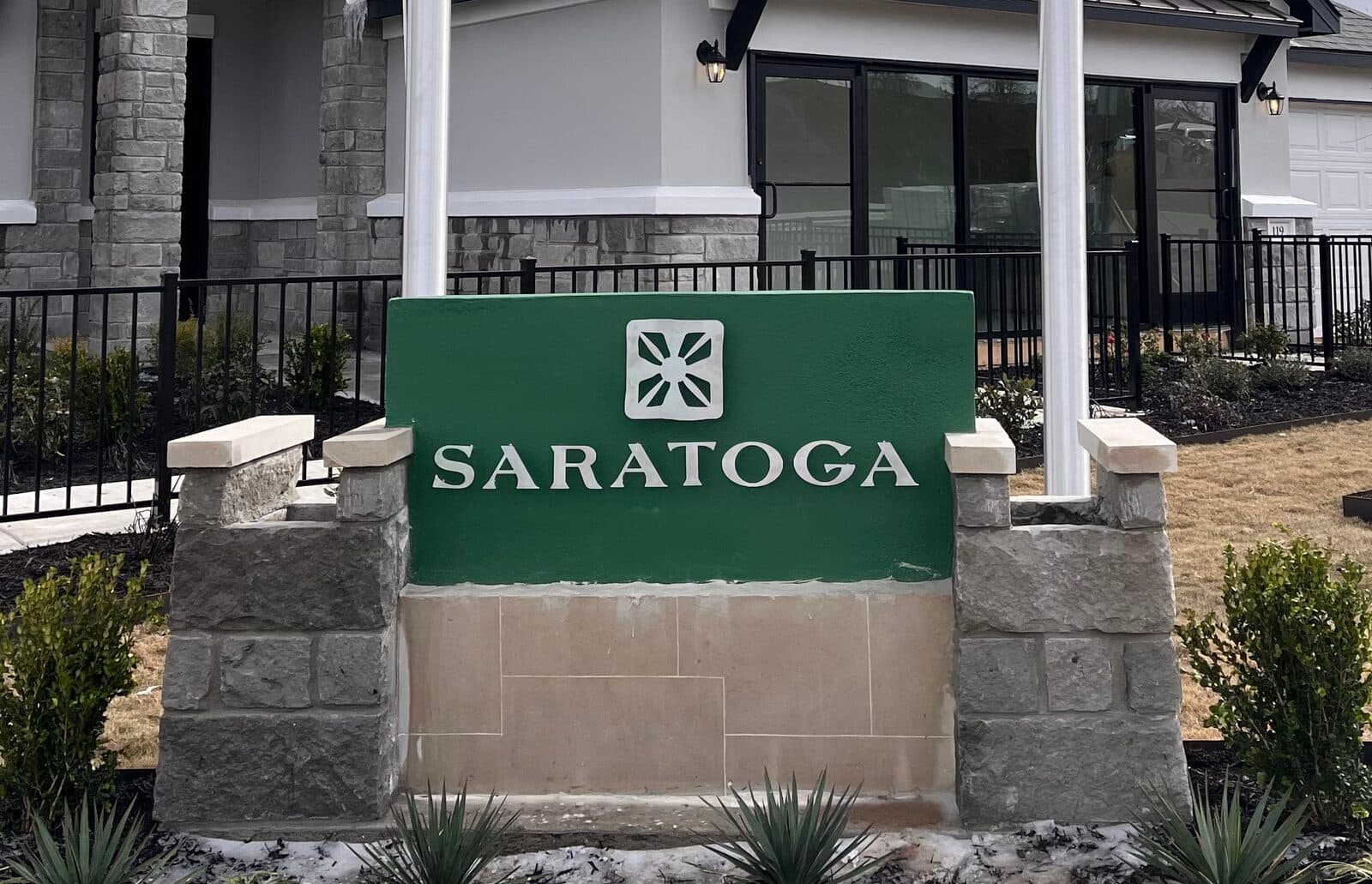 Community monument sign with brushed-metal dimensional letters on a stone base